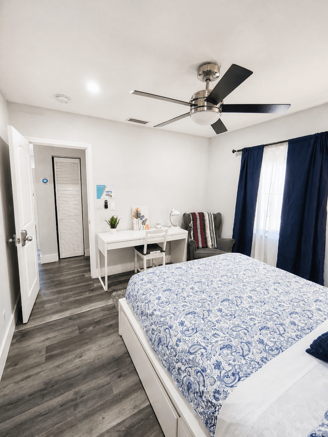 One-bedroom suite with storage bed, dedicated desk workspace, and navy blackout curtains