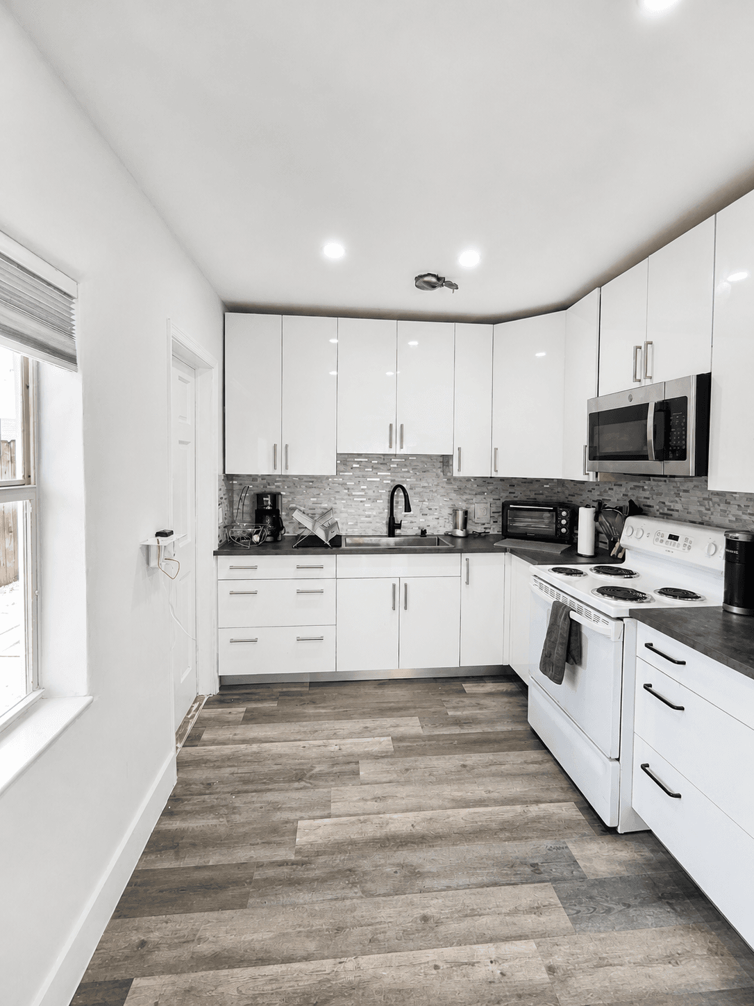 Full one-bedroom kitchen with white cabinets, stove, oven, microwave, and coffee makers