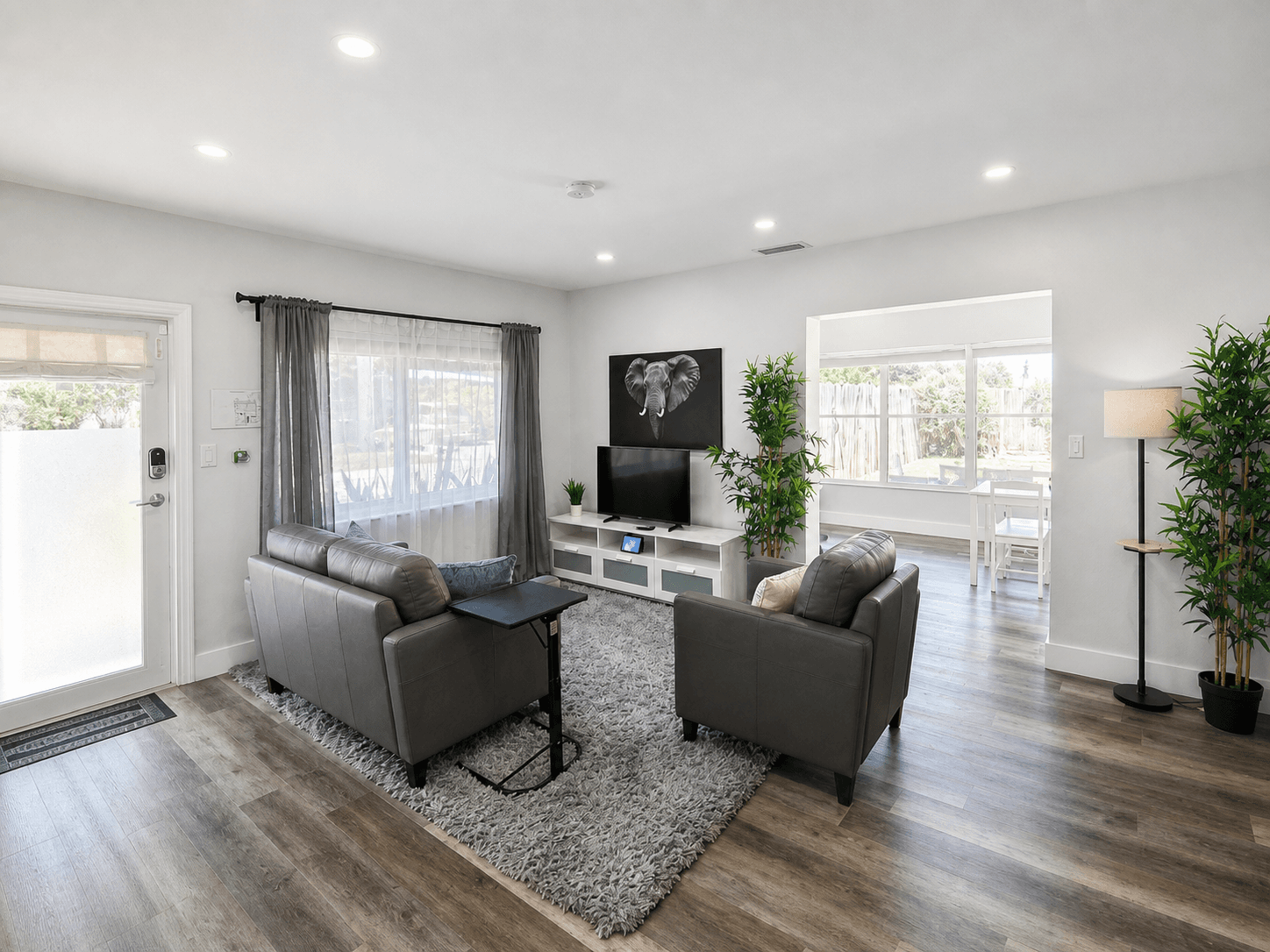 One-bedroom living room with grey leather seating, flat-screen TV, and smart-lock entry