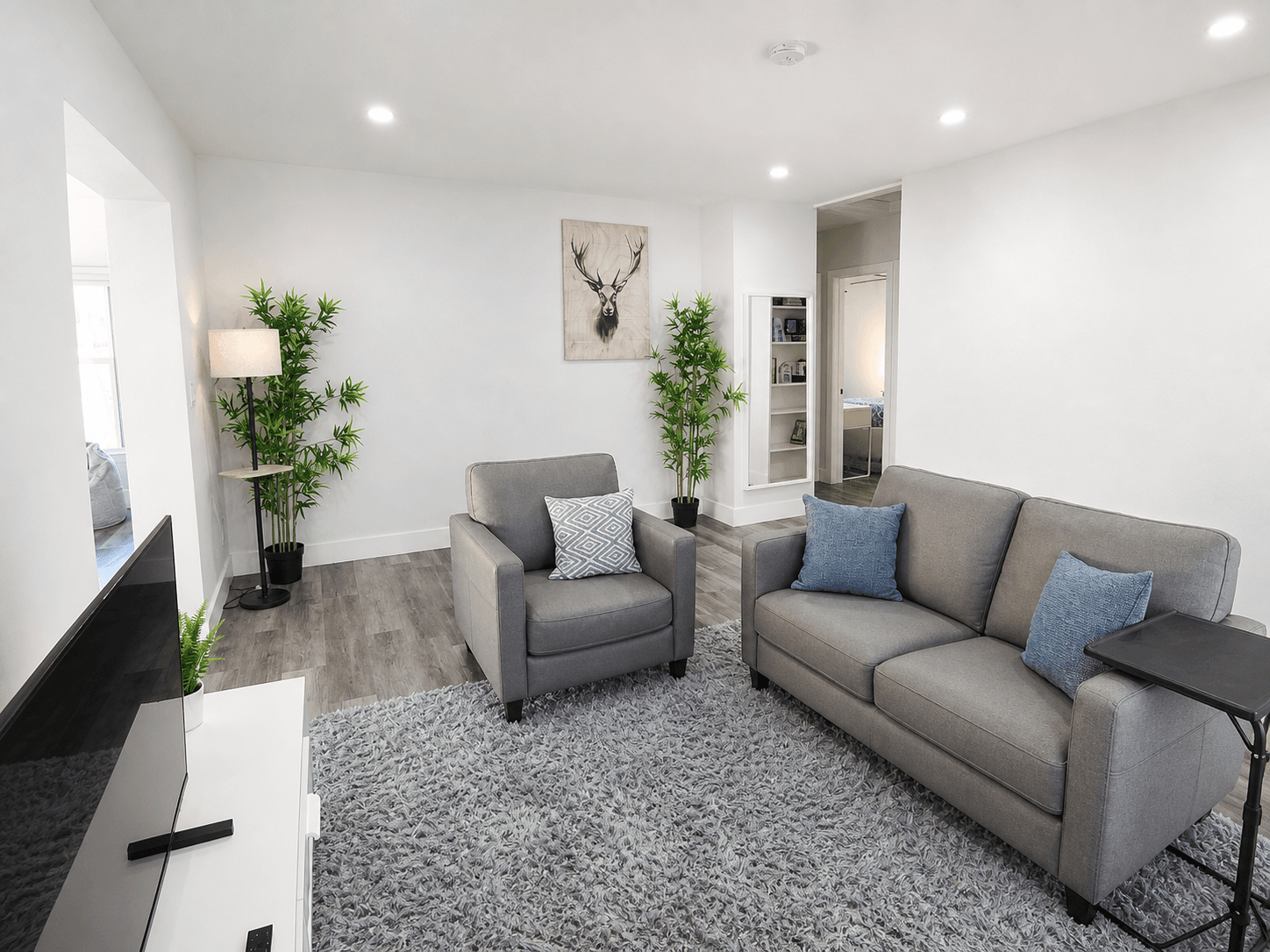 One-bedroom living area looking toward the bedroom with modern seating and recessed lighting
