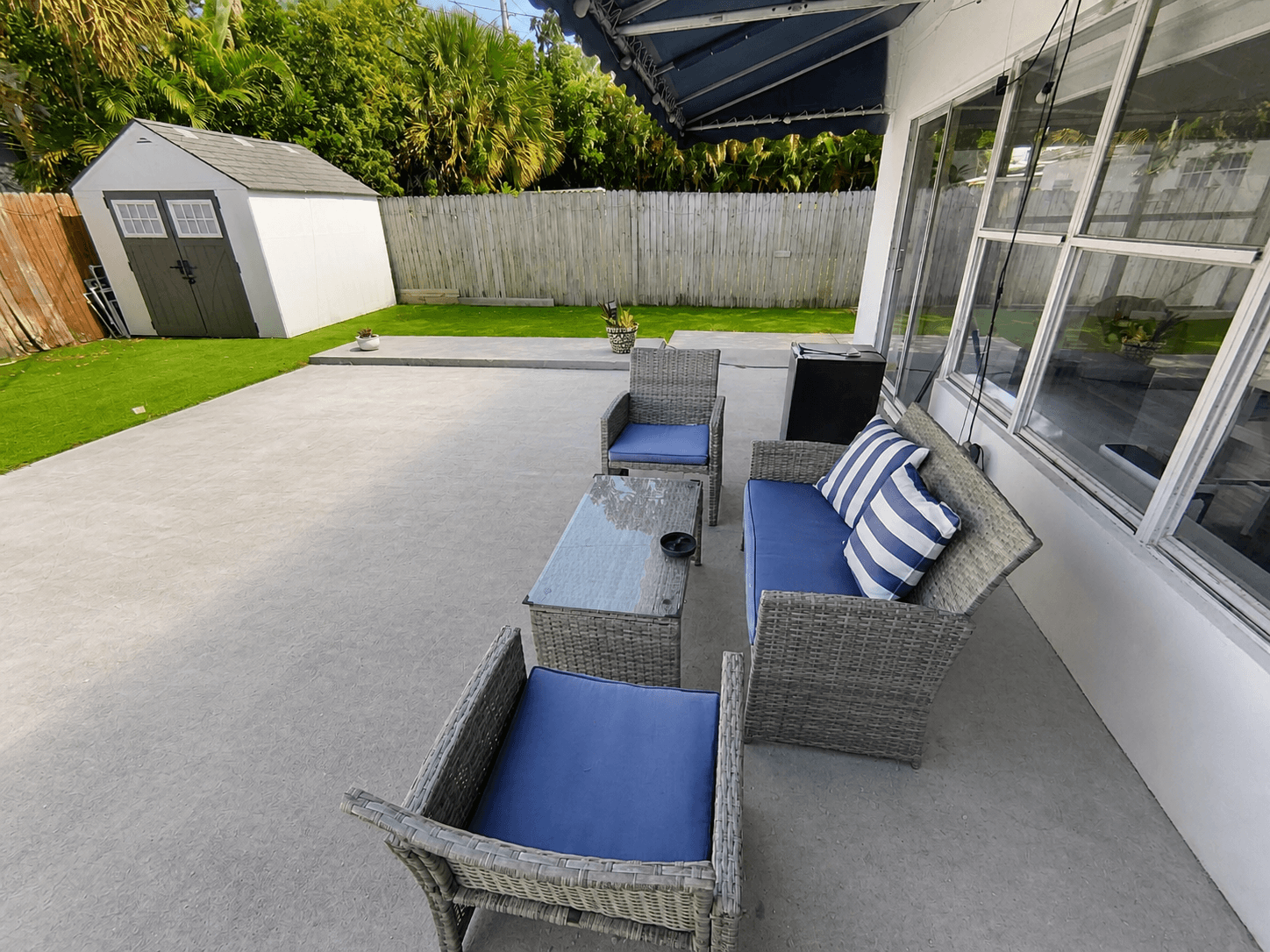 Covered patio lounge under a blue awning overlooking the private yard